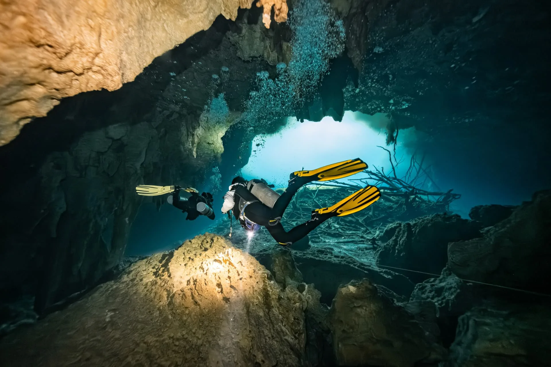 Two divers with lights entering the cavern area of Carwash cenote.