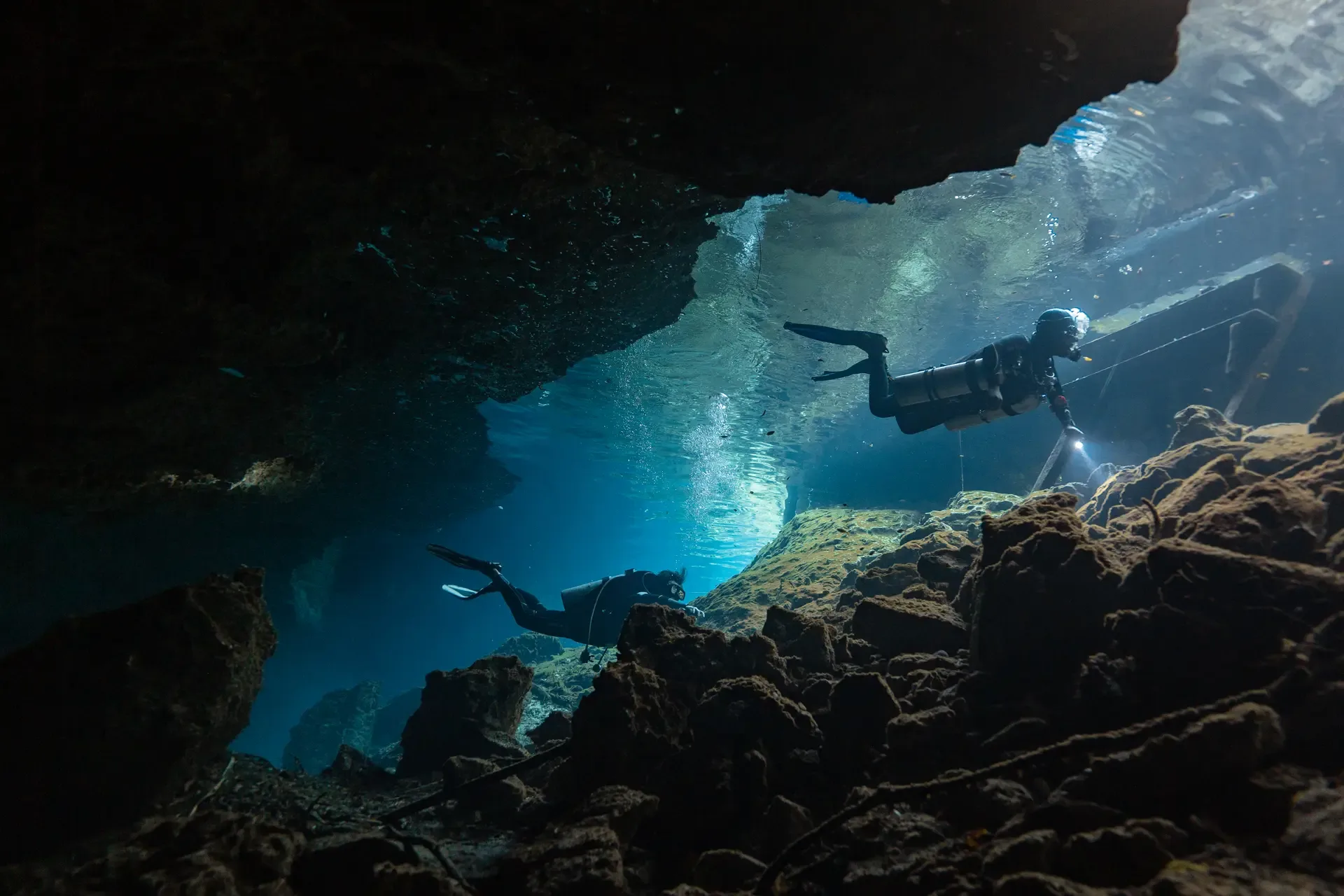 Two divers exploring the clear blue cavern at Nicte Ha cenote.