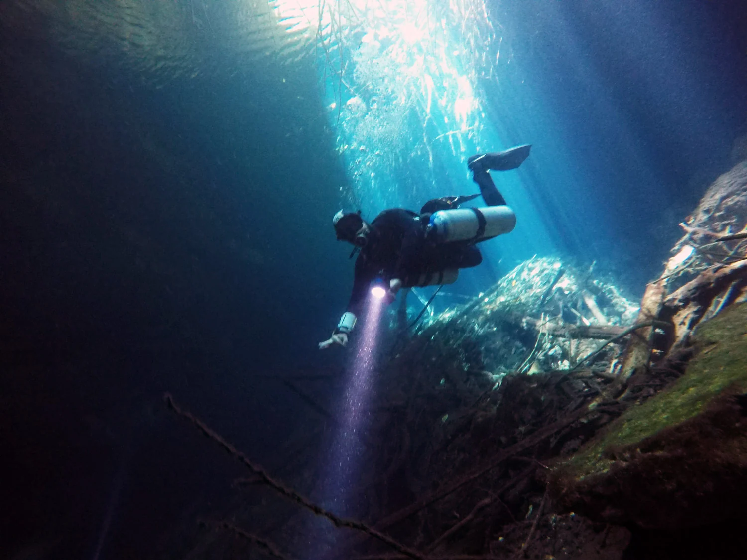 Diver beneath sunlight in El Eden cenote.