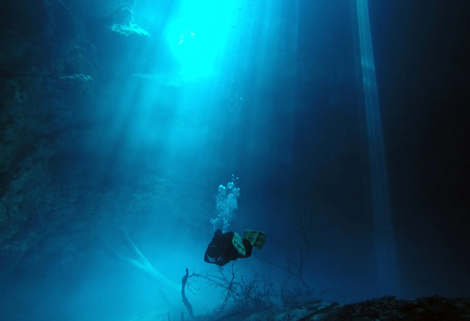Light beam falling through the water of The Pit with a diver beside it