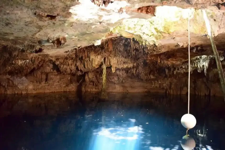 Daylight entering the blue water beneath the limestone ceiling at Kin Ha cenote.