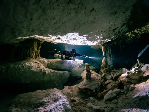 diver exploring Taak BiHa cenote with natural light and white rock
