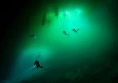 Buzos descendiendo en el cenote Orquídea rodeados por una haloclina que crea un efecto visual turbio