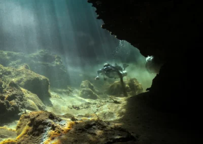 Buzo explorando una sección iluminada por rayos solares en Casa Cenote – fotografía subacuática de Iván García